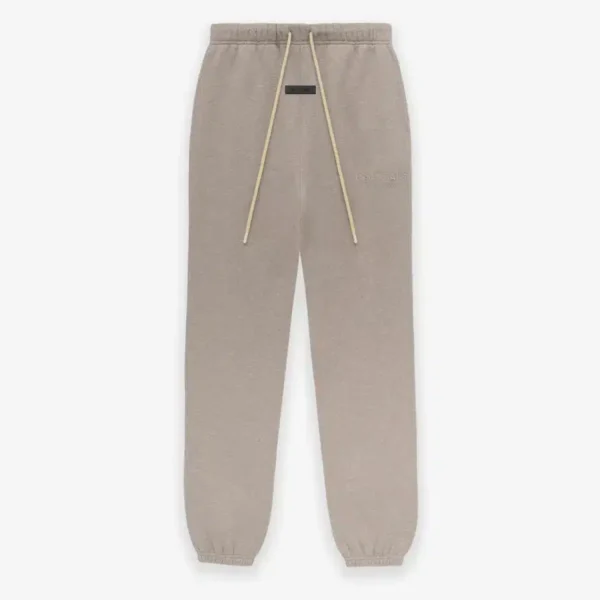 The 'Core-Heather' Fear of God sweatpants, which are tan with a drawstring waistband and elastic cuffs, are displayed against a plain background and showcase subtle branding on the front.