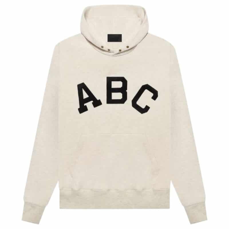 Fear of God Essentials ABC Hoodie 'Light-Oatmeal' featuring a cream-colored design with a hood, front pocket, and large black letters ABC printed across the chest.