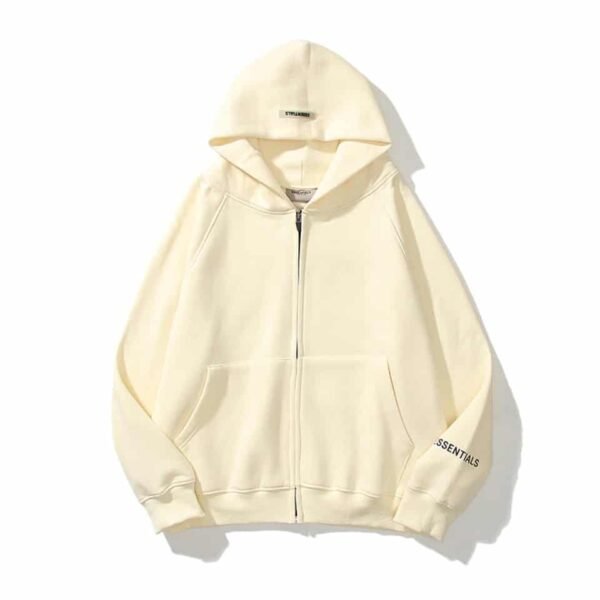 A cream-colored zip-up hoodie with a hood, called the Essentials Reflective Print Zip-up Oversized Cream Hoodie, featuring the word ESSENTIALS on the right sleeve. It is laid flat on a white background.