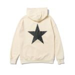 The Fear Of God Essentials Star Hoodie is cream-colored and features a large black star design on the back, complete with a drawstring hood and ribbed cuffs and hem.