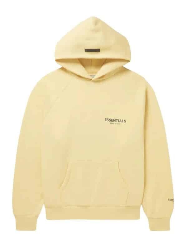 The Fear Of God Blend Jersey Essentials Hoodie is a light yellow hoodie featuring a front pocket, with "Essentials" and "Fear of God" printed in small black letters on the front and sleeve. It offers a relaxed fit and comes with a drawstring hood.